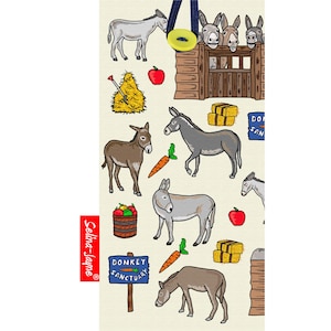 Könnte beinhalten: Eine bunte Tragetasche mit einem Muster aus Eseln, Heuballen, Äpfeln, Karotten und einem Schild mit der Aufschrift "Esel-Heiligtum". Die Tasche hat einen blauen Riemen und einen gelben Knopf.