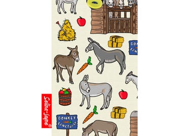 以下が含まれることがあります： ロバ、干し草の俵、リンゴ、ニンジン、そして「ロバの聖域」と書かれた看板の柄が描かれたカラフルなトートバッグ。バッグには青いストラップと黄色のボタンが付いています。
