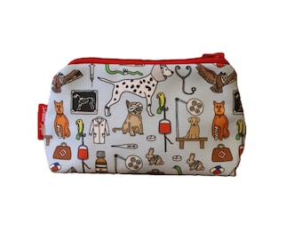 May include: A light blue zippered pouch featuring a repeating pattern of veterinary-themed illustrations. The design includes images of animals, medical tools, and a red zipper. The pouch has a red tag on the side.