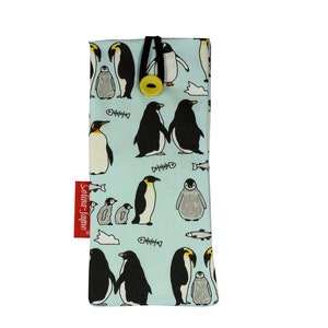 May include: A light blue fabric phone case with a repeating pattern of penguins and fish. The case has a black strap and a yellow button.