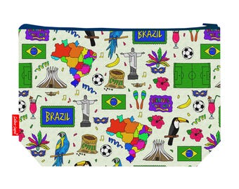 May include: A rectangular, zippered pouch with a cream background and a colorful Brazil-themed pattern. The design includes the Brazilian flag, maps, soccer balls, toucans, and the text "BRAZIL" and "BKAZIL". The pouch has a navy blue zipper.