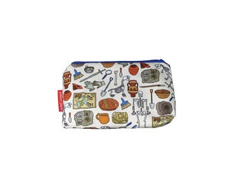 May include: A rectangular white zippered pouch with a blue zipper and a red tag. The pouch is covered in a repeating pattern of archeological tools, artifacts, and a skeleton in various colors.