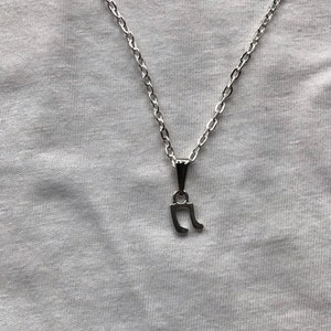 Puede incluir: Un collar de cadena de plata con un pequeño colgante de nota musical de plata.