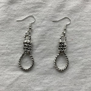 May include: A pair of silver earrings shaped like a noose. The earrings are made of a twisted metal chain.