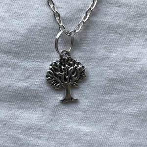 May include: A silver chain necklace with a tree pendant. The tree is detailed with branches and leaves.