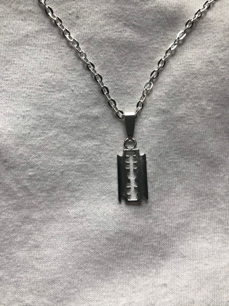 May include: A silver chain necklace with a razor blade pendant.