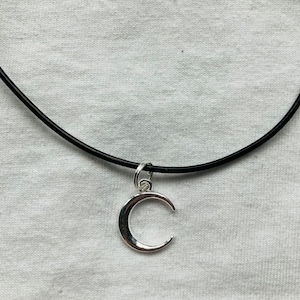 May include: A black choker necklace with a silver crescent moon pendant.