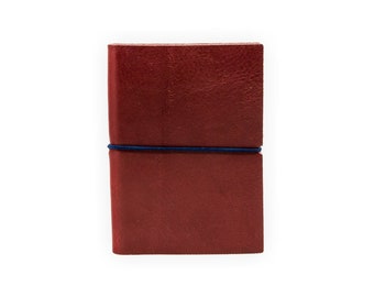 May include: A burgundy leather notebook with a blue elastic band closure.