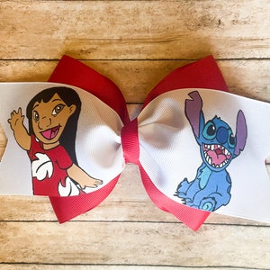May include: A large, layered hair bow featuring the characters Lilo and Stitch. The bow has a red base with white and red ribbon layers. Lilo is depicted waving, and Stitch is smiling. The bow is set against a wooden background.