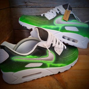 May include: A pair of white and green custom-painted Nike Air Max 90 sneakers with a black swoosh and green lightning bolt design.