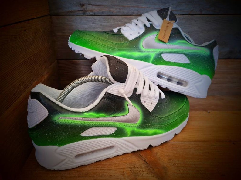 May include: A pair of white and green custom-painted Nike Air Max 90 sneakers with a black swoosh and green lightning bolt design.