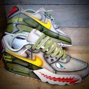 May include: A pair of custom-designed green and white sneakers with a shark tooth design on the sole. The sneakers have a yellow and orange flame design on the side and the text "Limited Edition" and "1 of 30" on the shoes.