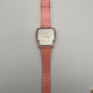 Puede incluir: Un reloj digital rosa vintage con una esfera rectangular y una correa a juego. El reloj tiene una caja de pl&aacute;stico y una parte trasera de acero inoxidable. La correa tiene m&uacute;ltiples orificios de ajuste. El reloj est&aacute; ensamblado en China.