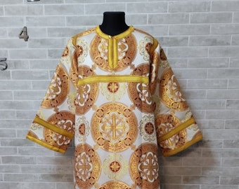 May include: A white liturgical robe with gold and red embroidery. The robe has a round neckline and long sleeves. The embroidery features a repeating pattern of circles with crosses inside.