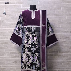 May include: A purple liturgical vestment with a black and silver brocade pattern and a matching purple stole. The vestment has a silver trim and a cross design.