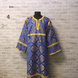May include: A blue and gold liturgical robe with a cross pattern. The robe has a high neckline and long sleeves.