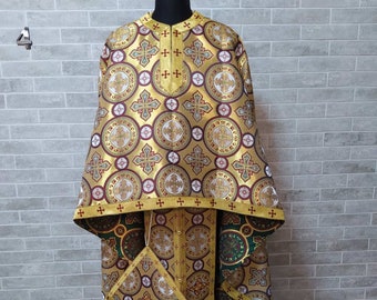 May include: A gold and red patterned liturgical vestment with a matching stole and pouch. The vestment has a circular design with crosses and other religious symbols.