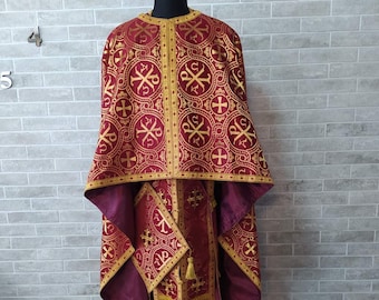 May include: A burgundy liturgical vestment with gold embroidery. The vestment features a cross pattern and intricate details.