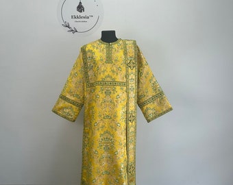 May include: A yellow and green patterned liturgical vestment with a cross design. The vestment is on a mannequin and has a long, flowing design.