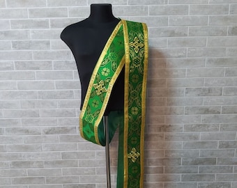 Könnte beinhalten: Eine grüne und goldene liturgische Stola mit einem dekorativen Muster. Die Stola wird auf einem Mannequin ausgestellt.