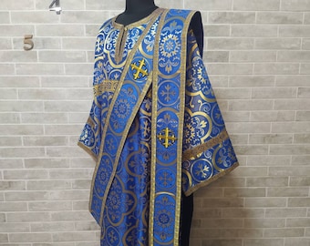 May include: A blue and gold liturgical vestment with a cross pattern. The vestment is made of a brocade fabric and has a long, flowing design.