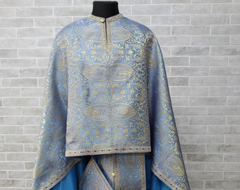 May include: A blue and gold liturgical vestment with intricate floral patterns. The vestment includes a long robe, a stole, and a small square piece of fabric.