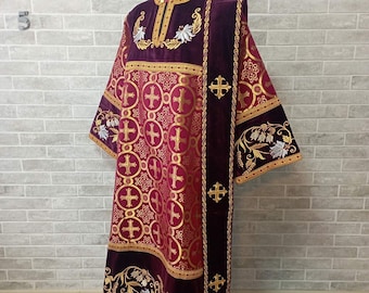 May include: Burgundy liturgical vestment with gold embroidery and a matching stole. The vestment features a repeating pattern of crosses and circles. The stole is trimmed with gold fringe.