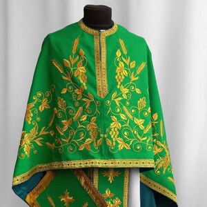 May include: A green liturgical vestment with gold embroidery of vines and grapes. The vestment has a white undergarment and a green stole with gold trim.