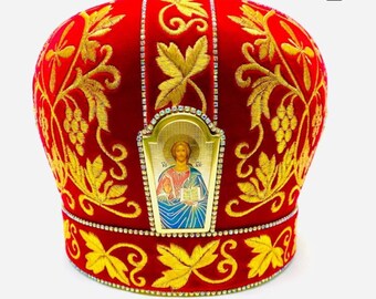 May include: Red velvet bishop's hat with gold embroidery of grapevines and leaves. The hat has a gold icon of Jesus Christ on the front.