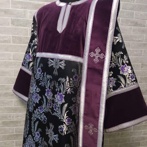 May include: A long, black and purple liturgical robe with silver floral embroidery and silver trim. The robe has a purple velvet collar and a purple velvet sash with silver crosses.
