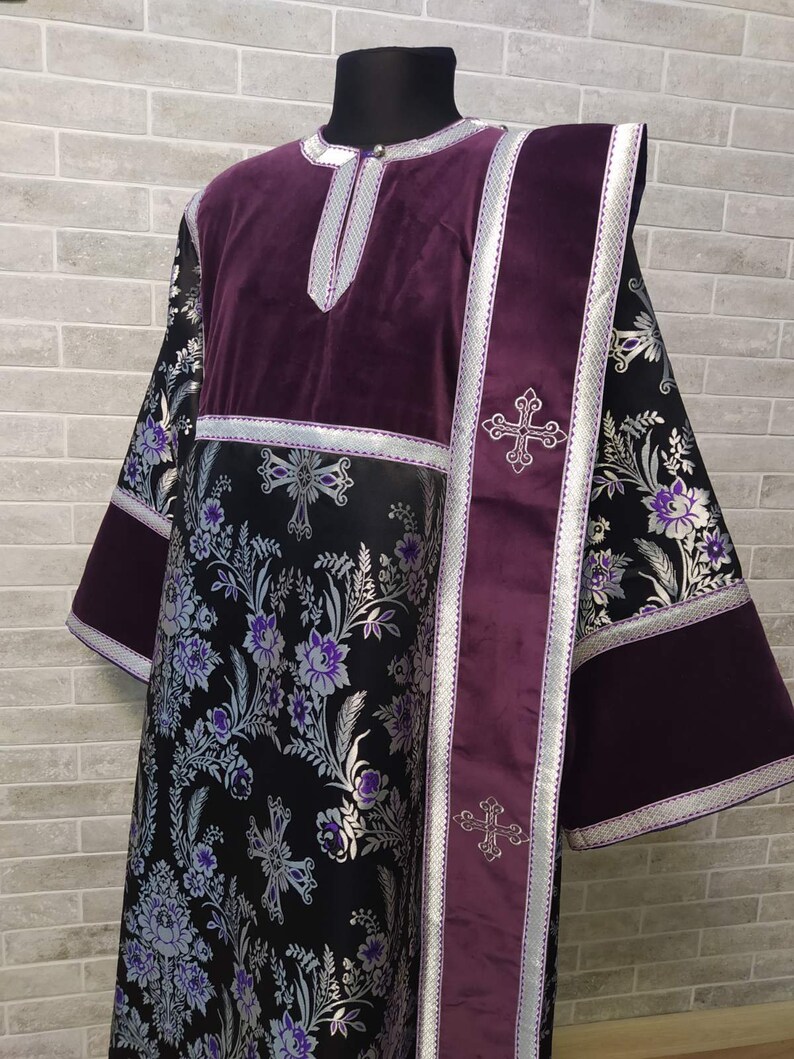 May include: A long, black and purple liturgical robe with silver floral embroidery and silver trim. The robe has a purple velvet collar and a purple velvet sash with silver crosses.
