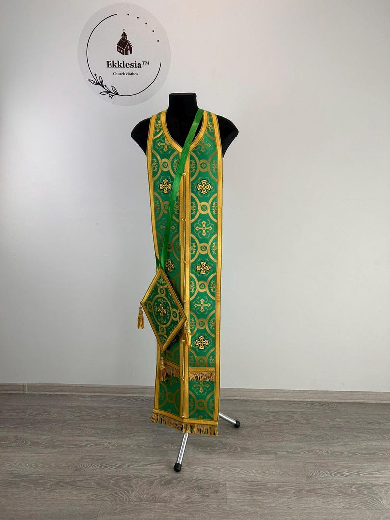 May include: Green liturgical vestment with gold embroidery and a matching green and gold pouch. The vestment is displayed on a stand.