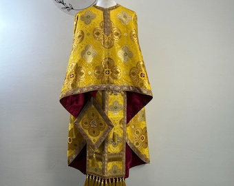May include: A bright yellow liturgical vestment featuring a repeating gold floral pattern and a deep burgundy lining. The garment includes a matching square accessory with gold tassels, intricate embroidery, and a central cross motif on the front.