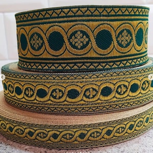 May include: Three rolls of gold and green trim with intricate patterns. The trim is woven with a repeating design of circles, swirls, and floral motifs.