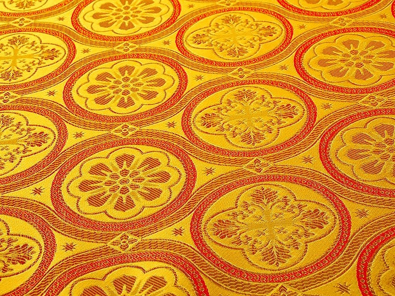 K&ouml;nnte beinhalten: Nahaufnahme eines goldenen Stoffes mit einem sich wiederholenden Muster aus roten und goldenen Kreisen. Die Kreise haben ein florales Design in der Mitte.