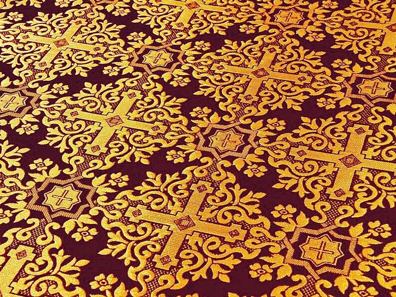Pu&ograve; includere: Primo piano di un tessuto bordeaux con un motivo dorato ripetuto. Il design presenta croci ornate ed elementi floreali, creando un aspetto ricco e strutturato. I dettagli intricati del tessuto suggeriscono un uso decorativo o cerimoniale.