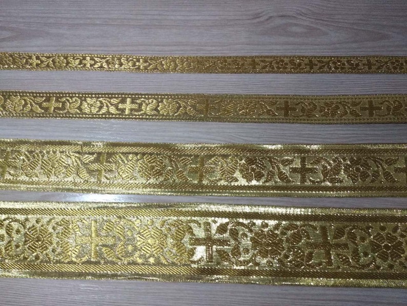 May include: Four gold-colored trims with a repeating pattern of crosses and floral designs. The trims are different widths and have varying levels of detail.