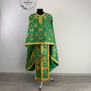 May include: Green and gold liturgical vestment with a cross pattern. The vestment is displayed on a stand.