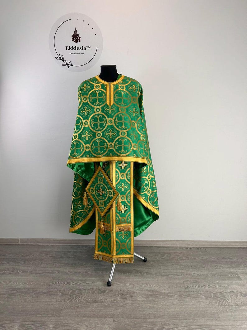 May include: Green and gold liturgical vestment with a cross pattern. The vestment is displayed on a stand.