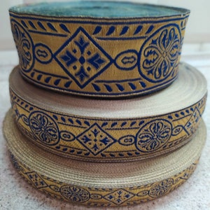 Puede incluir: Tres rollos de ribete dorado y azul con estampado. El ribete tiene un dise&ntilde;o geom&eacute;trico repetitivo con forma de diamante y motivos florales.