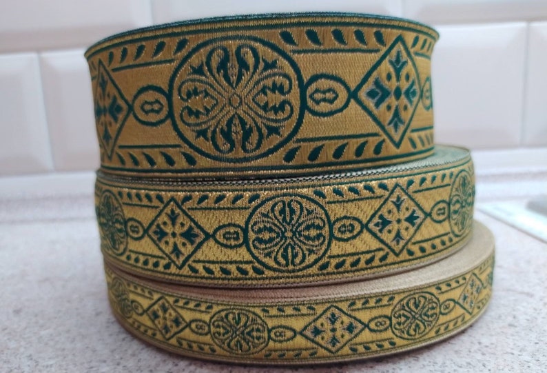 Puede incluir: Tres rollos de ribete estampado en dorado y verde. El ribete tiene un dise&ntilde;o geom&eacute;trico con un patr&oacute;n repetitivo de diamantes y motivos florales.