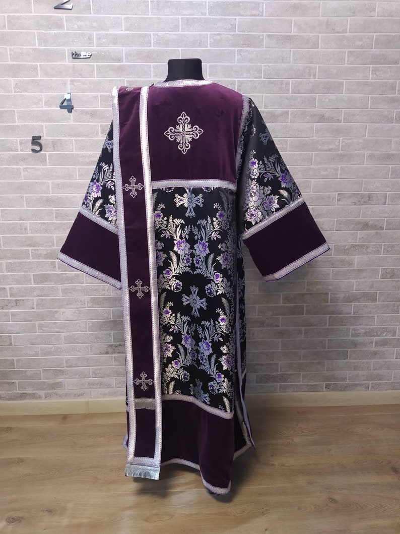May include: A black and silver brocade liturgical vestment with purple velvet accents. The vestment features embroidered crosses and floral designs.