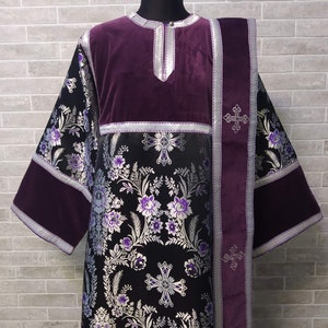 May include: A black and silver brocade liturgical vestment with purple velvet trim and a matching stole. The vestment features a floral pattern with silver crosses.