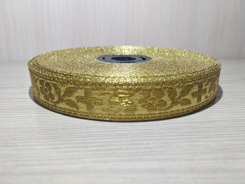 May include: Gold trim with a floral pattern. The trim is rolled up and ready to be used for sewing or crafting projects.