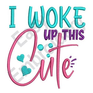 May include: Embroidered design with the text "I woke up this cute" in pink, blue, and purple lettering. The word "cute" is in a large, cursive font with two small hearts.