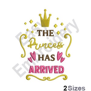 Puede incluir: Diseño de bordado dorado con una corona, estrellas y el texto "THE PRINCESS HAS ARRIVED" con corazones rosas. El diseño está disponible en dos tamaños.
