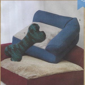 May include: A red and beige pet bed with a blue and beige bolster bed on top. A green and black bone-shaped stuffed toy is on the bed. The text "PET BEDS AND STUFFED PILLOW TOY" is at the bottom of the image.