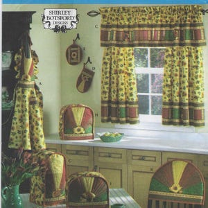 May include: A sewing pattern for a kitchen themed set including a valance, apron, toaster cover, chair back cover, and oven mitt. The pattern features a sunflower design with green, yellow, and brown colors.