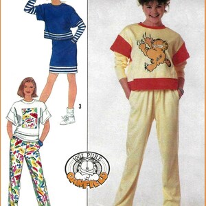 May include: A sewing pattern illustration featuring three outfits: a blue two-piece set with striped sleeves, a white t-shirt with abstract colorful shapes paired with patterned pants, and a yellow sweatshirt with a Garfield graphic and matching pants.