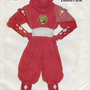May include: Red Power Ranger costume pattern. The costume is red with white and gold diamond accents. The pattern includes a hood, mask, and pants. The Power Rangers logo is visible on the top right corner. The text "Red Ninja Ranger" is at the bottom.
